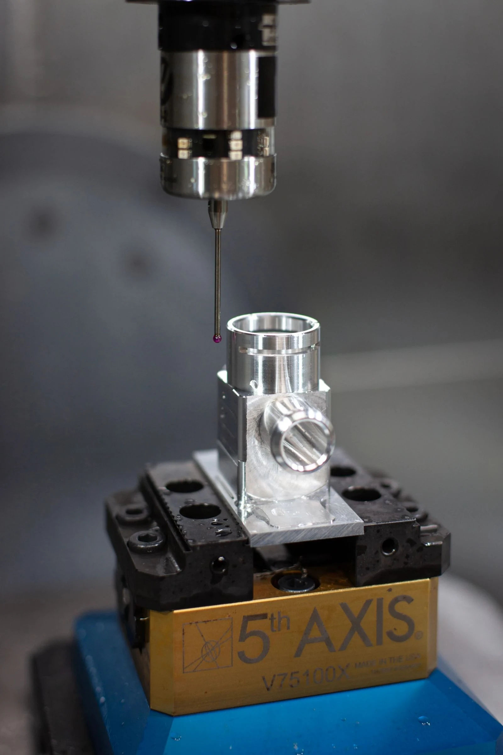 A probe checking a machined component held in a vise at Machinist Lab